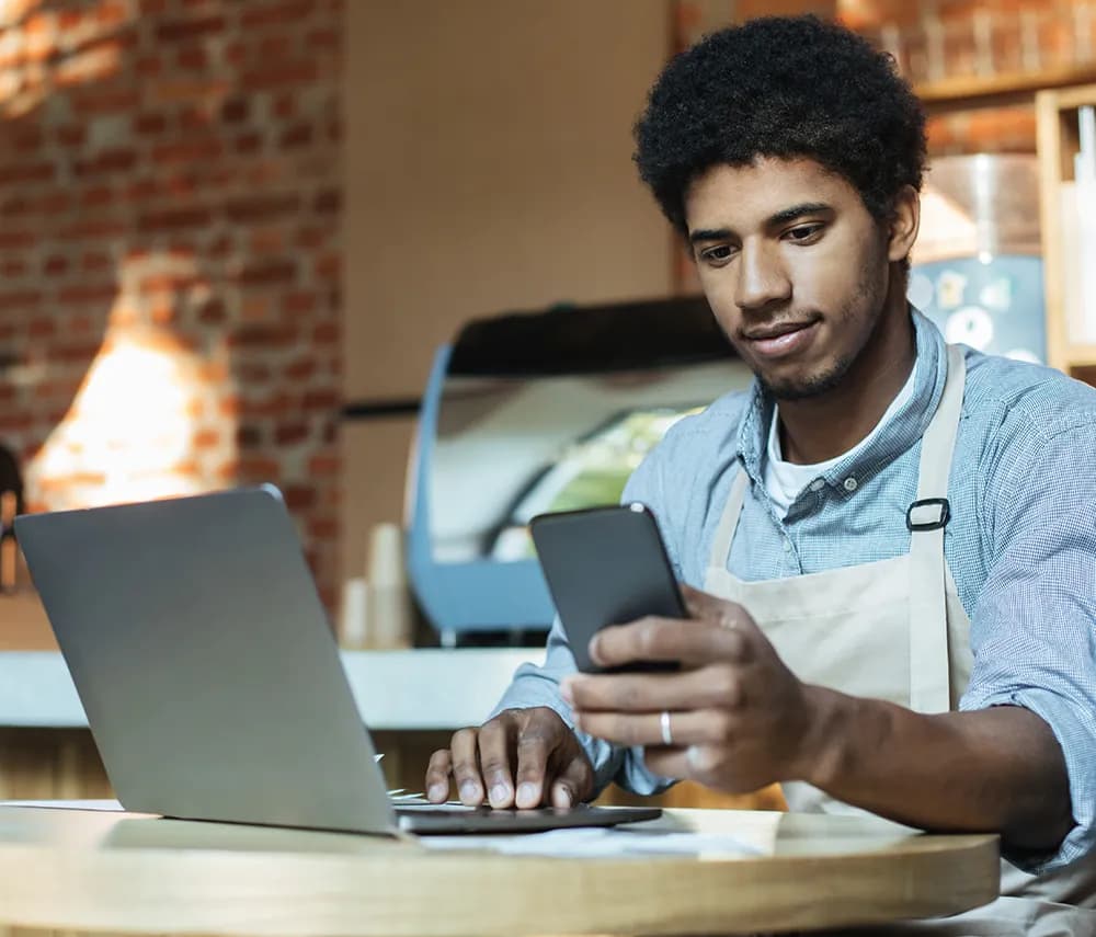 Restaurant operator checking CheddrSuite on phone and laptop